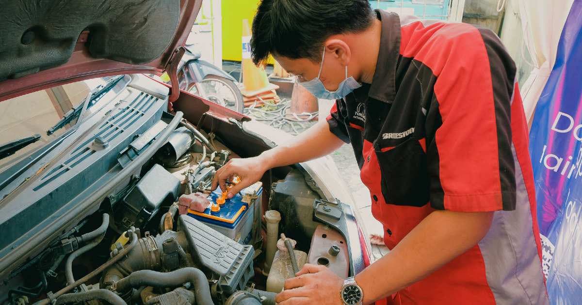 Teknisi melakukan penggantian aki mobil
